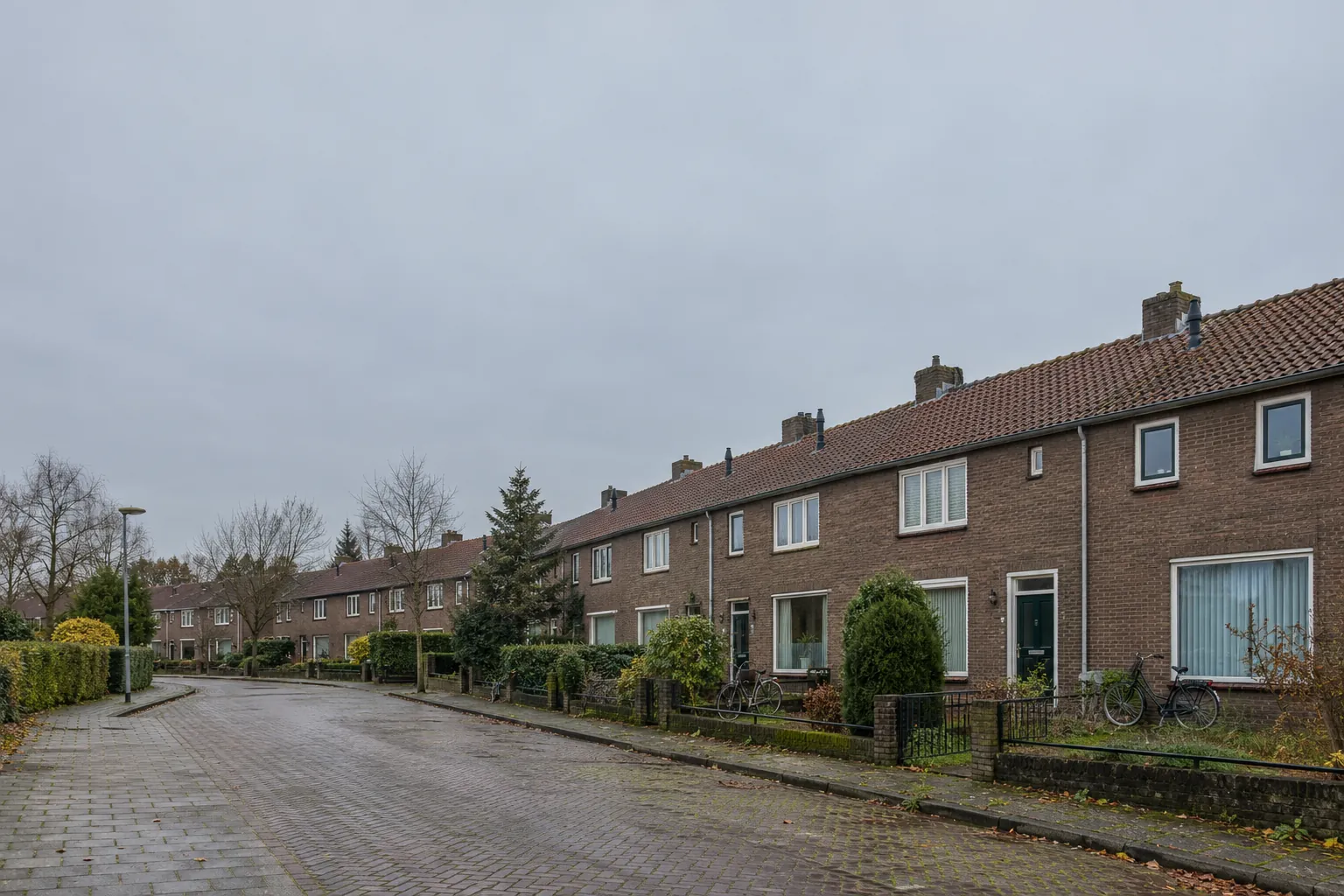 Een stille straat met rijtjeshuizen van baksteen en voortuintjes in een oude mijnwerkerswijk.